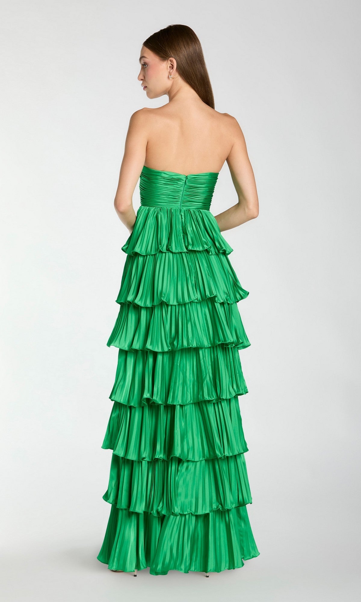 A woman faces away in the Long Formal Dress: Mac Duggal 49981, a strapless ruffle gown with tiered layers, set against a plain light background.